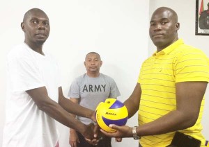 Public Relations Officer of the Guyana Volleyball Federation (GVF), Mark Bradford (left), presents a volleyball to newly elected President of the Demerara Volleyball Association in the presence of GVF President, John Flores