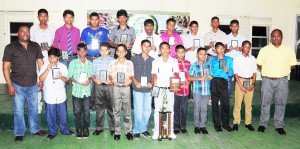 Members of the victorious ECC U-13 team display their accolades with president  of the club Stephen Lewis (left) and coach Shaheed Mohamed (far right).