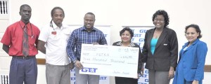 GT&T Senior Marketing representative Anjanie Hackett hands over the cheque to Petra Organisation Co-Director Troy Mendonca in the presence of fellow staffers and officials yesterday.