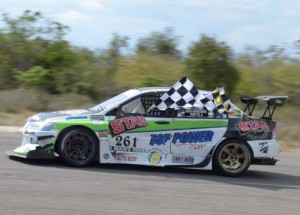 The king of the newly constructed Jamwest Speedway Guyana’s Kristian Jeffrey displays the chequered flag following one of his three victories on Sunday. 