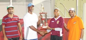 Permanent secretary of the MCYS Alfred King (left) presents the winning trophy to Airport XI captain Teekaram Narine in the presence of other players. 