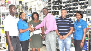 Supervisor of 2Js General Store, Loyette Barnwell hands over the cheque to Petra Organisation’s Mark Alleyne in the presence of Co-Director Troy Mendonca (2nd right), Ohnioca Brammah (centre) and staffers.