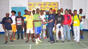 Busta representative Ravin Singh (4th right) presents a team Captain with their prize money in the presence of other team reps on Sunday.