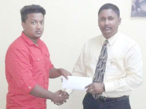 Mahendra Persaud Baichan, son of sponsor presents cheques to Vicky Bharosay, member of the organising committee.  