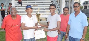Mr. Steven Seeraj (right), son of the late Parbattie Jaggai hands over the winner trophy and Stationery Voucher to Captain of Skeldon High. Also in photo are UCCA President Mr. Dennis De Andrade (far right) and other executives of the UCCA.