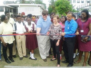 Composite picture cutting the ribbon to the INtegrated Model Farm is Mia a representative of Olderndorf Carriers with assistance from Charge D Affairs OF The US embassy in Guyana Brian Hunte, CEO of FFP Ken Vincent, Andrea Benjamin, Project Manager of FFP, two students and Reverend Dr. SElby Ross.  
