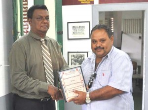 GCB President Drubahadur is presented with a plaque by GCC's Honorary Secretary Jameel Baskh as Vice President Ramsay Ali share the moment at Bourda yesterday.