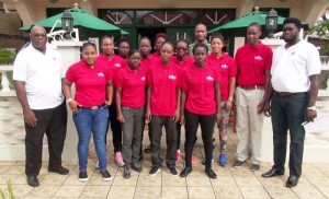 The National female basketball team along with Coaches, Julian Haynes (left), Kirk Fraser (right) pose for a photo opportunity with GABF President, Nigel Hinds (fourth, right, back row) outside the Windjammer International Hotel yesterday morning before departure to the British Virgin Islands to play in the Caribbean Championships.