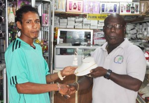 Managing Director of Junior’s Elegant Jewellery and Pawnshop Ferdinand Bacchus (right) hands over the goal chain to Dwayne Lowe yesterday. 