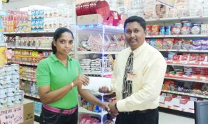 UCCA treasurer and BCB executive Vicky Bharosay (right) collects sponsorship from Vadisha Ragbeer, employee of Price is Right.