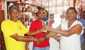 Captain of Underdog team James Ramnarine (right) accepts the winning trophy from Toolie Sheriffudeen in the presence of sponsor Safraz Sheriffudeen. 