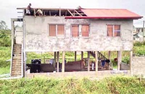 Residents of Parfait Harmonie replacing their roof which was blown off by the high winds.    