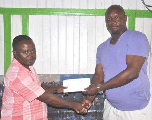 CEO of Big Boss Transportation Service Lyndon Boston (right) accepts the cheque from Osaffo Adams of Sweet Point. 