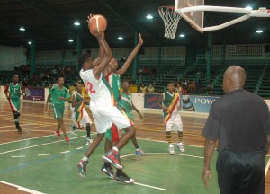 Kwakwani’s forward, Jamal Gilkes (left) goes up for a baseline fade-away jumper but Bishops’ centre, Timothy Thompson confronts him in the air last night at the Cliff Anderson Sports Hall.