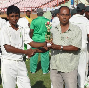 Left arm spinner Kelvin Umroa gets his MOM award for Selector Nazimul Drepaul after taking 5-32 against the Windwards yesterday.