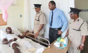 Commissioner of Police Seelall Persaud (left), Crime Chief Wendell Blanhum (centre) and Divisional Commander Clifton Hicken visit the wounded policeman.    