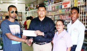 From left; Rovin Desouza, representing Jumbo Jet, receives the package from Supervisor Davendra Ramatalli as Lisa Khan and Marlon Khadoo shares the moment.