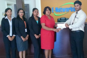 Mahendra Ramdihall, BCB representative (right) collects sponsorship cheque from ENetworks Berbice Manager Janet Seepersaud in the presence of other staff members. 