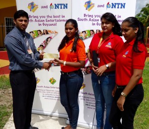 Mahendra Ramdihall (left) receives the sponsorship cheque from Nalinie Ganeshnauth of NTN TV in the presence of her colleagues.