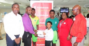 Scotiabank Business Banking manager Richard Damond presents the cheque to young Romeo Deonarain in the presence of from left Alfred Mentore, Ashmead Nedd, Sachin Singh, relationship officer Karen Harris and Brain Hackett. 