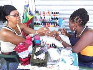  A street-side cosmetologist attending to her client’s nails 