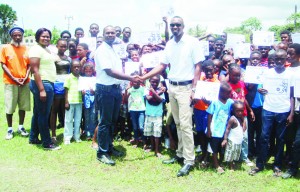 The children display their certificates while Director of Sport, Christopher Jones congratulates President of the FCFC, Wayne Forde, for a well organized summer camp. 