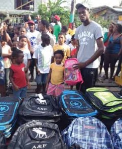 Positive Vibes Andre July, a Police Constable and promoter, hands over some of the 140 bags to children in his community 
