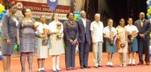 President David Granger is flanked by Ministers of Education, Dr Rupert Roopnaraine, and Ms Nicolette Henry, some of the top performers, QC’s Principal Ms Jackie Benn (second from left), Permanent Secretary of the Ministry of Education, Ms Delma Nedd (extreme left), and Chief Education Officer, Olato Sam.