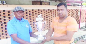 Former cyclist Deolall Sooklall (right) presents a trophy to coach Randolph Roberts. 