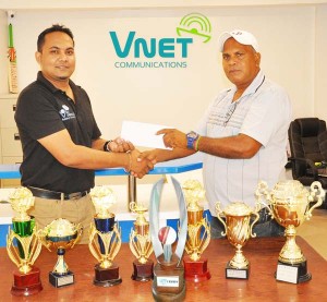 Chief Executive Officer of the V Net Communications Safraz Sheriffudeen (left) presents the cheque to WCC chairman Moses Ramnarine while some of the prizes are on display. 