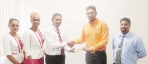 From Left to right are: Rabindranauth Basil, Assistant Manager of Diamond Fire & General Insurance hands over settlement cheque to Ridwan Khan who received it on behalf of RNK Investment Inc. 