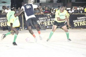 A player from Castello Housing Scheme (centre) tries to dribble past a member of the Alexander Village unit in their clash on Saturday.