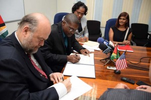 Airport Security: US Ambassador, Perry Holloway and Public Works Minister, David Patterson, signing the agreement yesterday. At right is GCAA’s Director General (ag.), Chaitrani Heeralall and Minister within the Ministry of Public Infrastructure, Annette Ferguson.