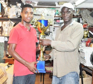 Tournament Organiser Mark Wiltshire (right) receives one of the trophies up for grabs from Trophy Stall staffer Travis Brandon at the entity’s location, Bourda Market.