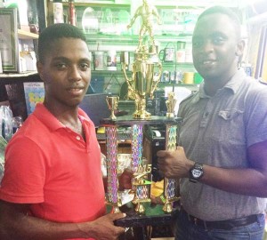 Trophy Stall representative, Travis Brandon (left) hands over the Championship Trophy for NEE Futsal Tournament to Aubrey Major Jr. 