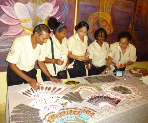 Artistes In Direct Support members and Director Desiree Edghill (far right) in discourse over a table of exhibits used to pass on the message of protection and prevention against HIV/AIDS