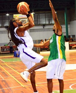 Guyana’s Travis Burnett (right) forces a fade-away jumper from Antigua’s Adisa Harris Monday night at the Cliff Anderson Sports Hall.