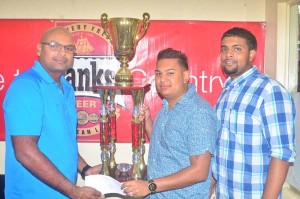 Justin Ally collecting the trophy- Justin Ally (centre) collects the trophy for the feature race from Banks DIH rep Gavin Jodhan in the presence of Nasrudeen (Jumbo Jet) Mohamed Jnr. 
