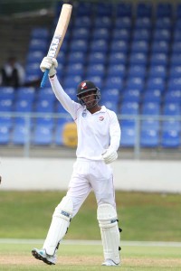 Uhtman Mohammed raises his bat after reaching 50 on debut.