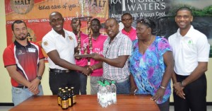 West Demerara Football - Banks DIH Limited non-alcoholic brand manager Clayton McKenzie (left) presents the winner’s trophy to WDFA President Orin Ferrier, while other officials of the sponsor and club enjoy the moment.