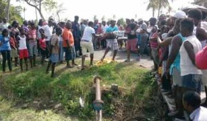 Villagers watch as police remove the dead man from the scene.  