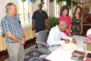 President Granger signs the Dharm Shala’s Visitor’s Book after participating in the annual Christmas luncheon with residents, as Mr. Edward Boyer of National Hardware (left), Ms. Kella and Ms. Pamela Ramsaroop (right) look on.