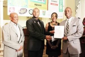 Alex Bunbury (right) receives his certificate of ambassadorship to the GFF from its President Wayne Forde, while Mayor Hamilton Green (left) and Minister Nicolette Henry (2nd right) share the moment at Cara Lodge Saturday.