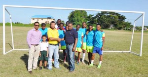 Petra Organisation Director Troy Mendonca (right front row) hands over the goals to Ministry of Ediucation representative Nicholas Fraser in the presence of Dr. Dennis Bassier (left) and members of reigning Milo champions Chase Academy yesterday.