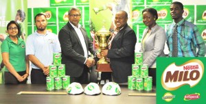 Nestle Caribbean Development Manager Sudesh Mahase (3rd left) hands over the championship trophy to Petra Organisation Director Troy Mendonca in the presence of GFF 3rd V-President Thandi McAllister (2nd right), Ministry of Education rep Nicholas Fraser (2nd left), Milo rep Renita Sital (left) and Petra official Mark Alleyne (right) yesterday. 