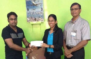 Muneshwers Travel Consultant, Mr. Colin Changur hands over sponsorship funds to GSSF President, Ms. Vidushi Persaud. At right is GSSF Board Member, Dr. Bhiro Harry.