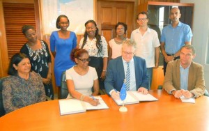 Ambassador Videtiè and Ms Madray affix their signatures to the contract in the presence of EU Delegation and Childlink Inc officials.