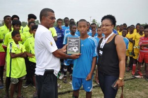 Mr. Indar Jaigobin, Marketing Assistant of Continental Agencies Limited hands over the Fair Play Plaque to Soesdyke Falcons Captain Tyrone Khan. At right is club President, Roxanne Dey.