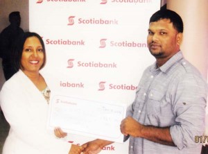 Scotia Bank Marketing Executive Ms. Jennifer Cipriani hands over cheque to RHTY&SC’s Executive, Mark Papannah. 