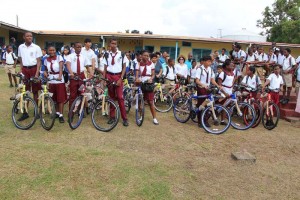 Minister of Social Cohesion, Ms. Amna Ally, First Lady Mrs. Sandra Granger, and other government officials stand among the students as they proudly display their new bikes, courtesy of President David Granger’s ’Three Bs’ initiative.  